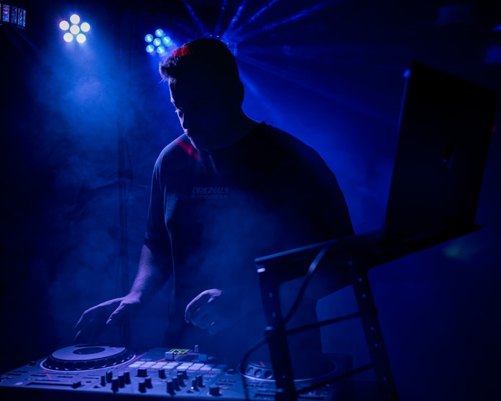 DJ Jannis am Pult im Club, blaues Licht und Nebel